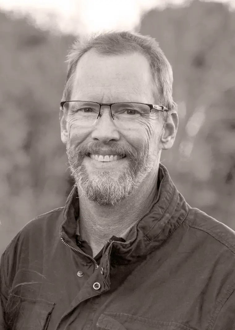 Bill Grady, creative director, smiling outdoors in a green jacket